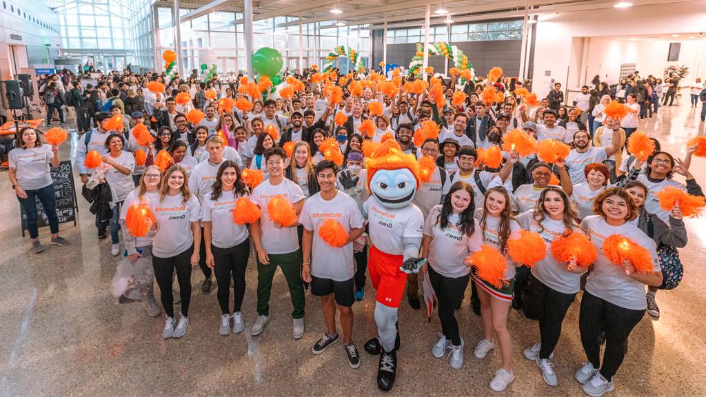 学生们围着彗星Temoc(吉祥物)，手里拿着橙色的绒球